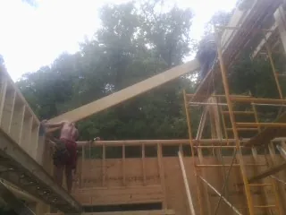Carpenter raising a rafter beam on a new second story frame in Sandy Hook