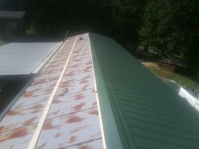 Old rusted panels beside newly installed green metal roofing — Wind Damage Roof Repair by Roofing Brothers in Sandy Hook
