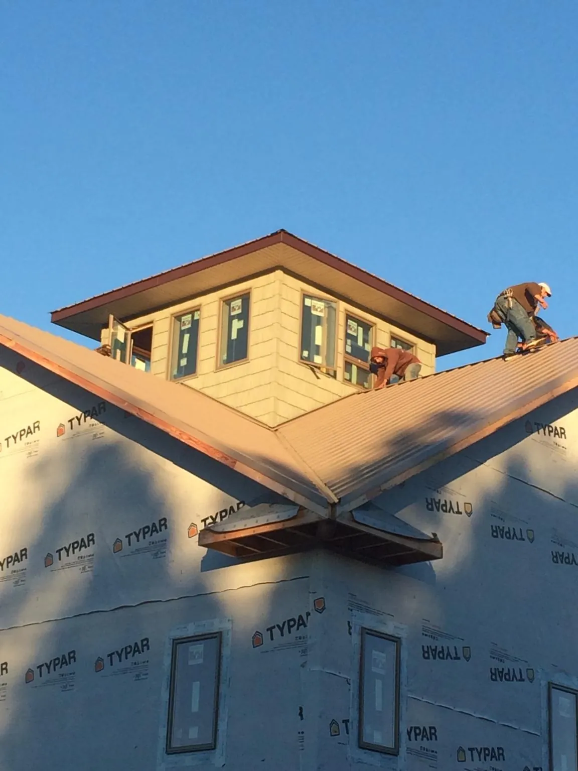 Roofers working around a rooftop cupola on a new metal roof at sunset — Roof Waterproofing in Sandy Hook by Roofing Brothers